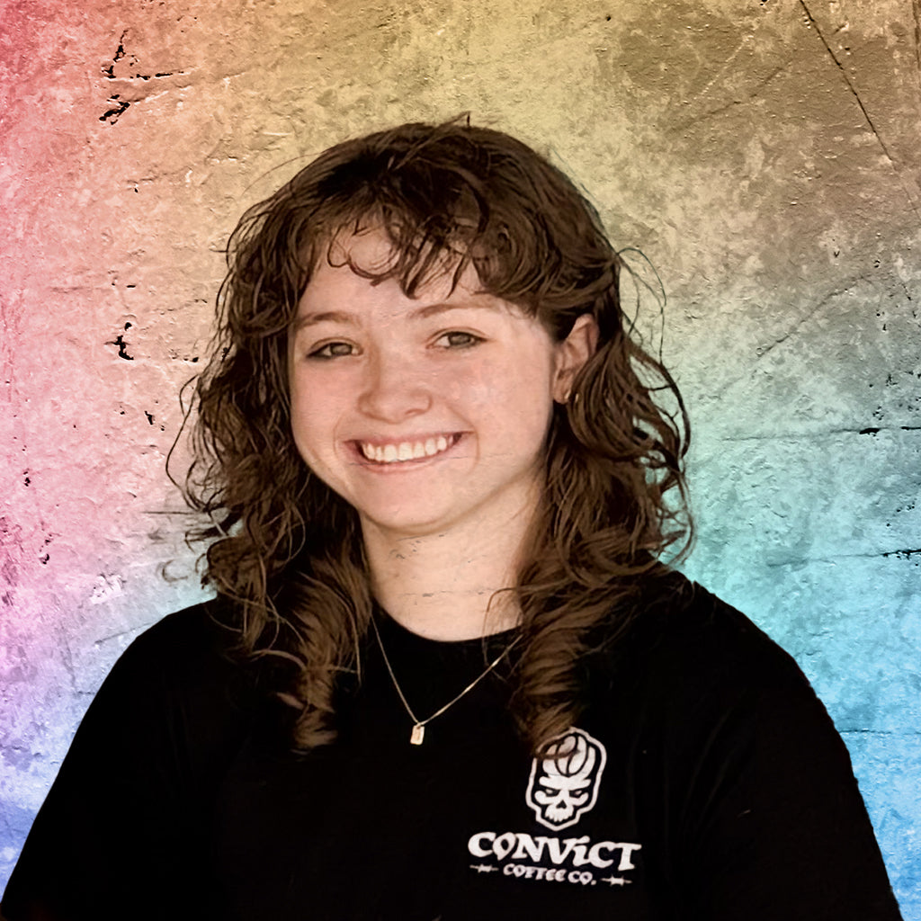 Briget Zwiezen wearing a black shirt with a logo and text against a colorful, textured background