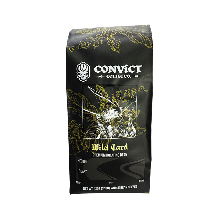 A 12 oz bag of Convict Coffee Co. Wild Card Premium Rotating Bean coffee, featuring a black bag with gold botanical illustrations and white text.