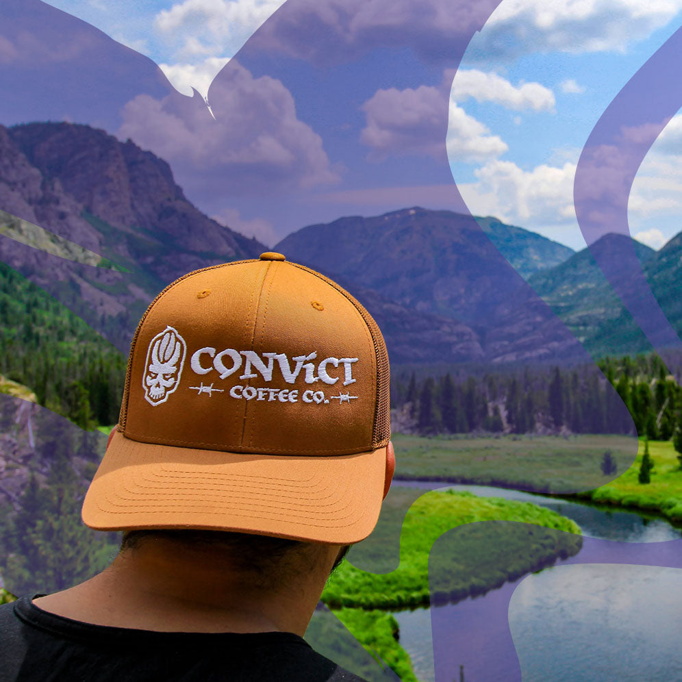 Person wearing convict coffee hat in front of landscape