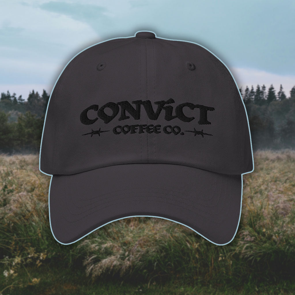 Dark Grey Dad Hat with 'Convict Coffee Co.' logo black embroidery on a grassy foggy field background