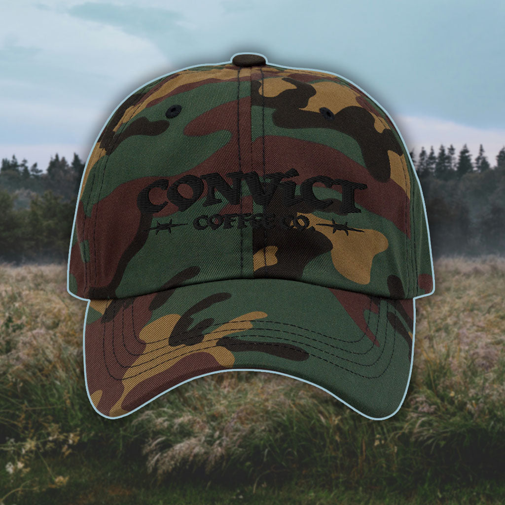 Green Camo Dad Hat with 'Convict Coffee Co.' logo black embroidery on a grassy foggy field background