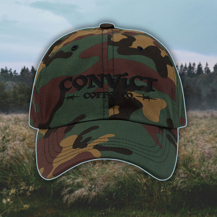Green Camo Dad Hat with 'Convict Coffee Co.' logo black embroidery on a grassy foggy field background