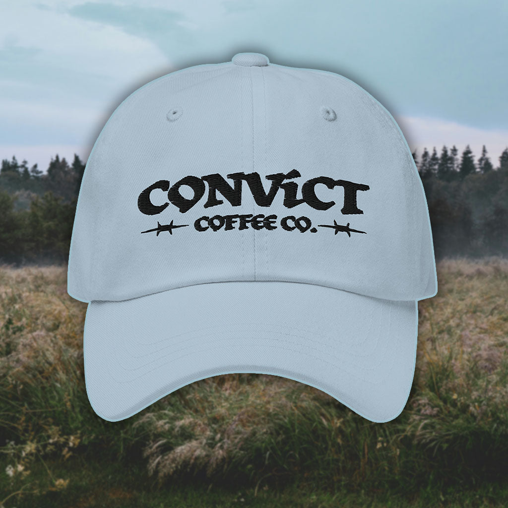 Light Blue Dad Hat with 'Convict Coffee Co.' logo black embroidery on a grassy foggy field background