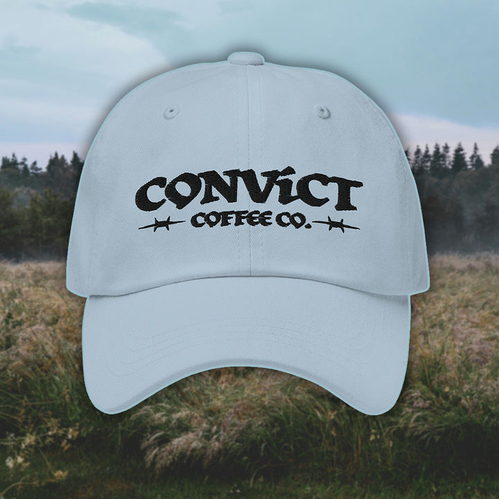Light Blue Dad Hat with 'Convict Coffee Co.' logo black embroidery on a grassy foggy field background