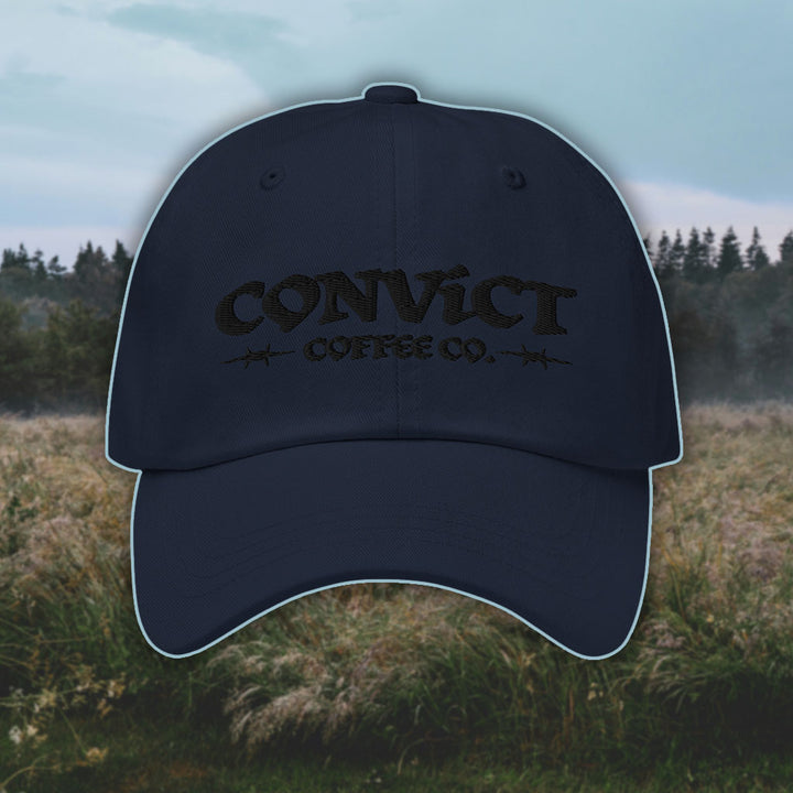 Navy Dad Hat with 'Convict Coffee Co.' logo black embroidery on a grassy foggy field background