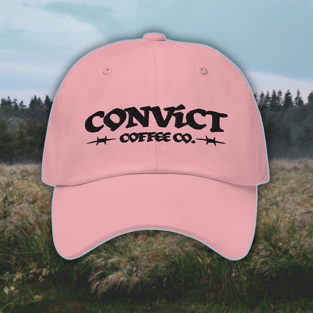 Pink Dad Hat with 'Convict Coffee Co.' logo black embroidery on a grassy foggy field background