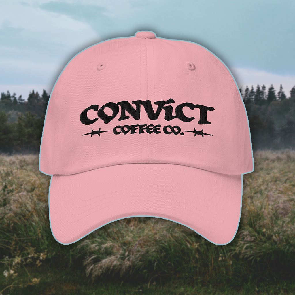 Pink Dad Hat with 'Convict Coffee Co.' logo black embroidery on a grassy foggy field background