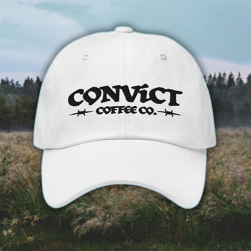 White Dad Hat with 'Convict Coffee Co.' logo black embroidery on a grassy foggy field background