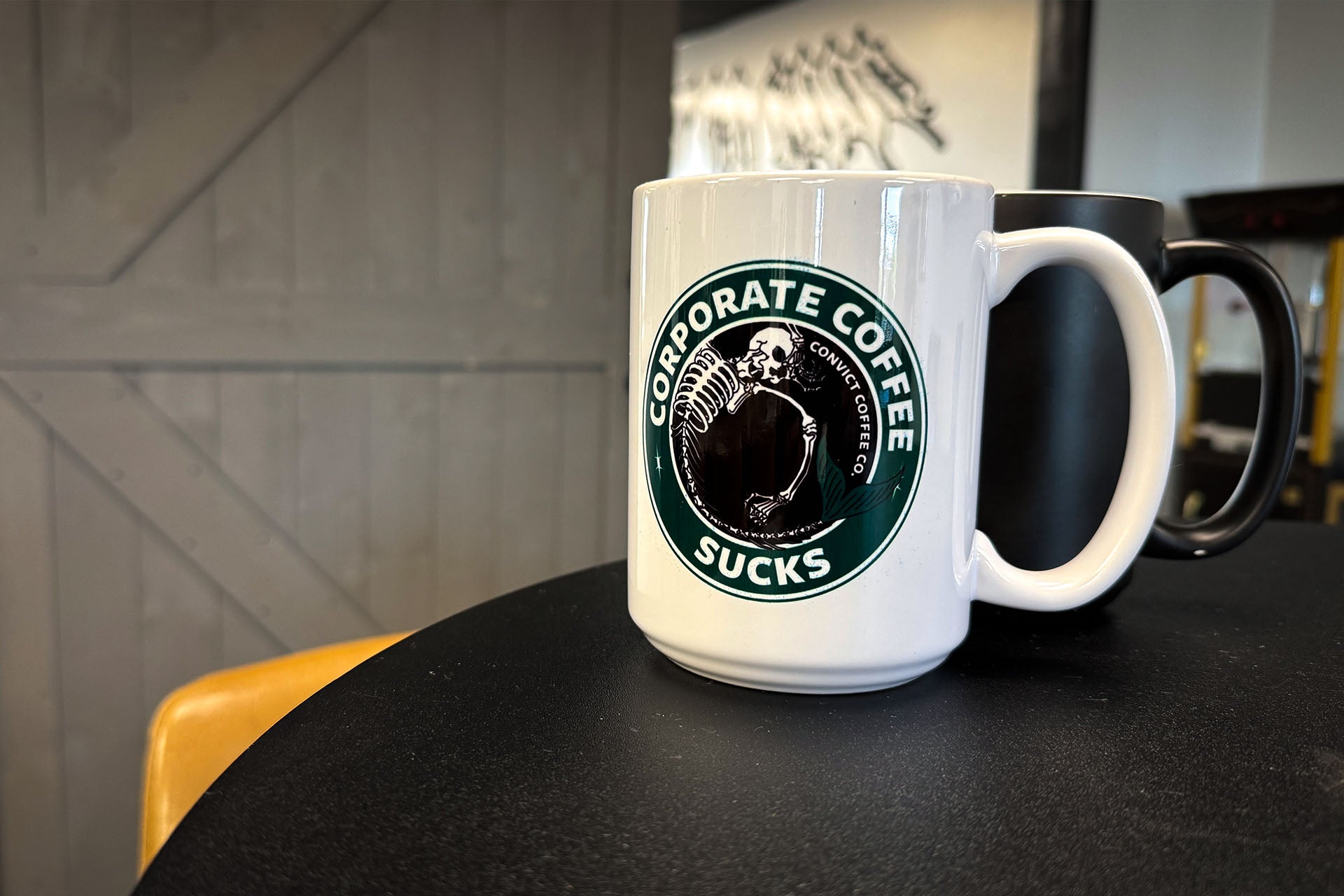 White mug with 'Corporate Coffee Sucks' design on a black surface