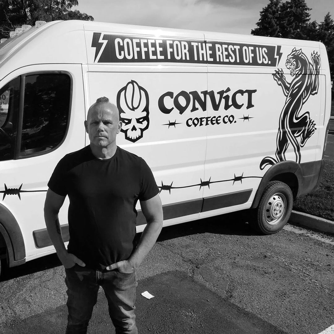 Man standing in front of a white van with 'Convict Coffee Co.' branding black and white