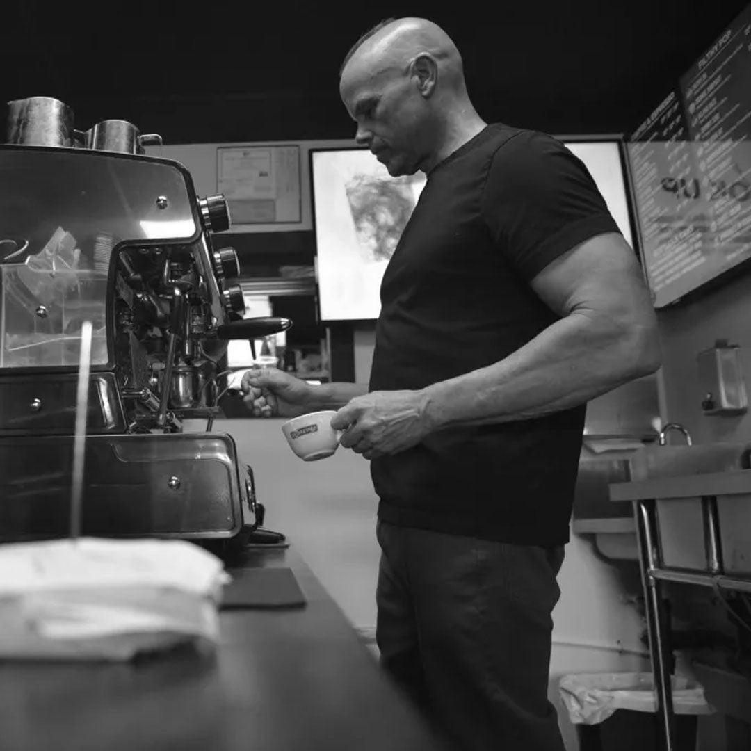 Dan Klehm working with a coffee machine in a kitchen setting black and white