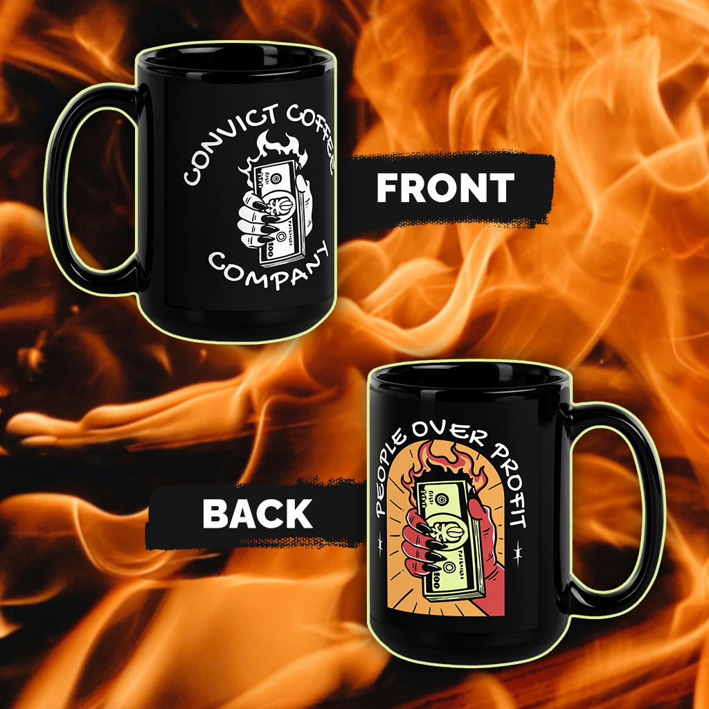 Two black mugs with on a fiery background, with 'people over profit' colorful hand holding burning money design on back and 'convict coffee company' white hand holding burning money on front