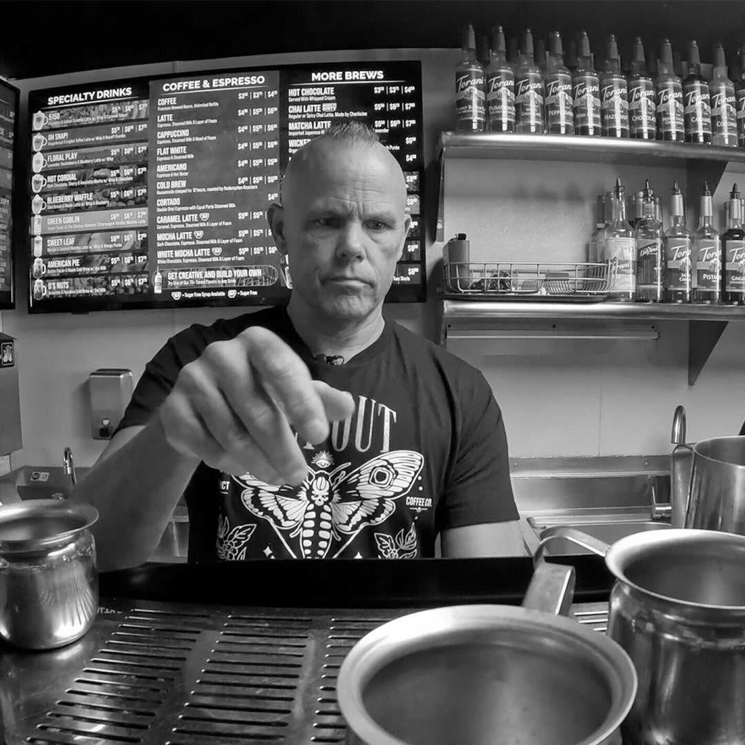 Dan Klehm reaching for pitcher in a coffee shop setting black and white