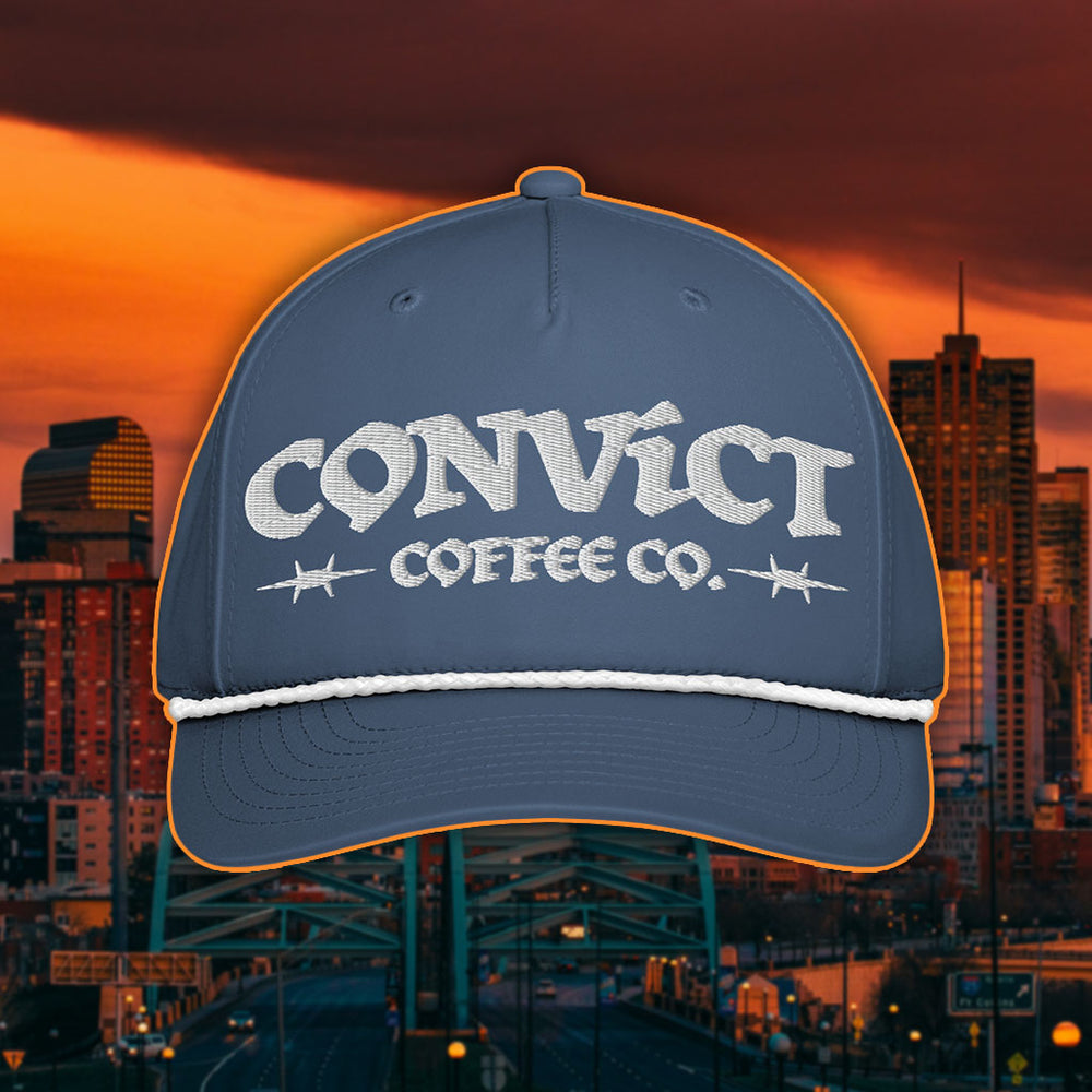 Light Blue Rope Hat with White Rope and 'Convict Coffee Co.' logo white embroidery on a Denver Cityscape Background at Sunset