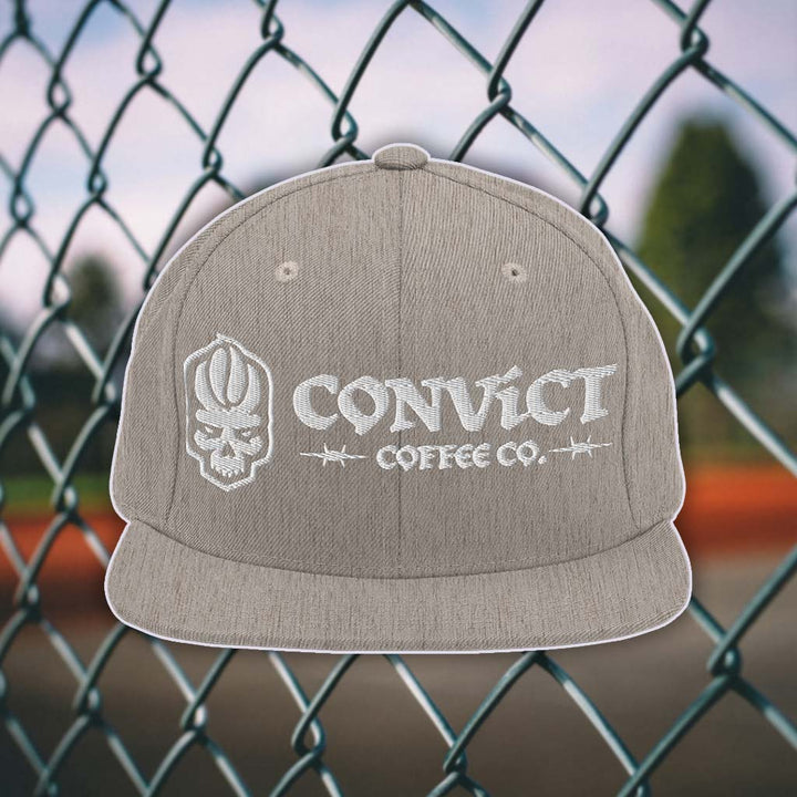 Heather Grey snapback flat bill with 'Convict Coffee Co.' logo white embroidery on a chain-link fence background