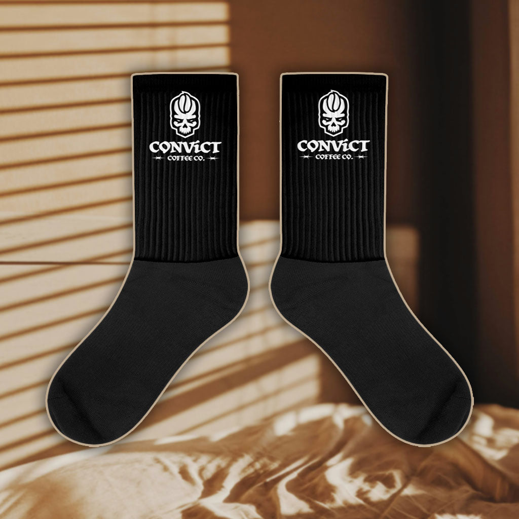 Black socks with a white Convict Coffee Co Logo on a bedroom background