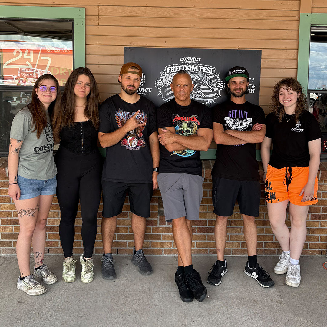 Group of six people (Ava Hendren, Jade Davis, Daniel Klehm, Dan Klehm, Damien Klehm, Briget Zwiezen) posing in front of a brick wall with a sign in the background.
