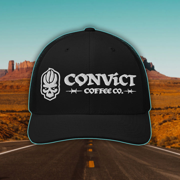 Black Trucker Hat with 'Convict Coffee Co.' logo white embroidery on a Desert Road background