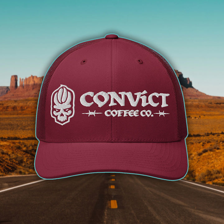 Cranberry Trucker Hat with 'Convict Coffee Co.' logo white embroidery on a Desert Road background