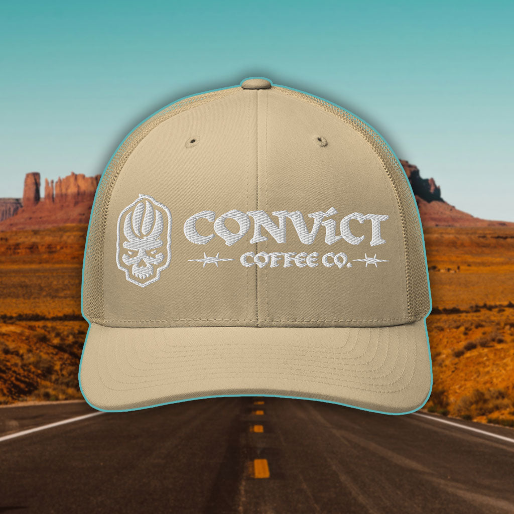 Khaki Trucker Hat with 'Convict Coffee Co.' logo white embroidery on a Desert Road background