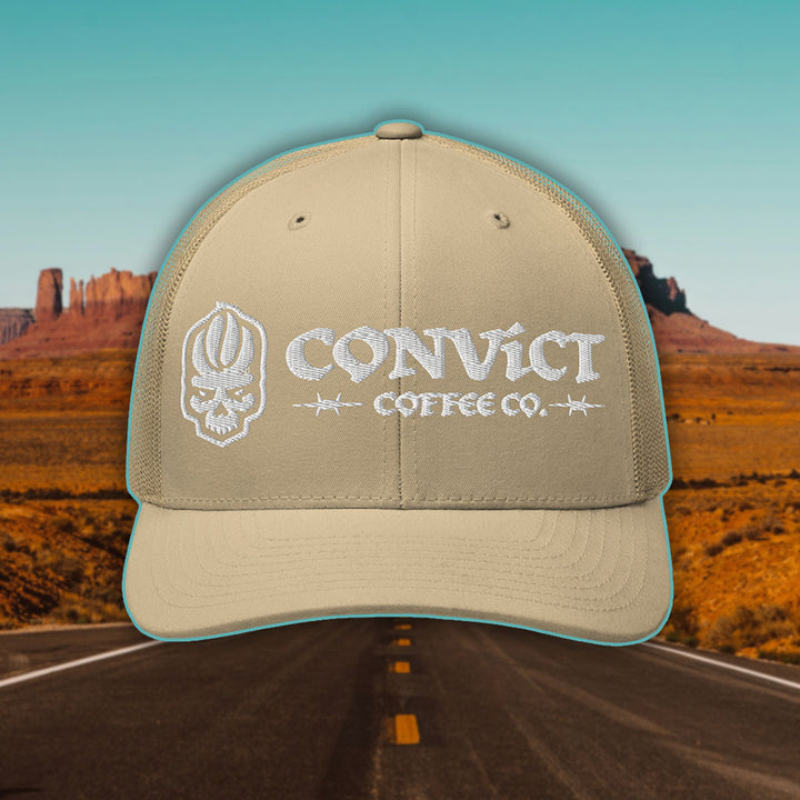Khaki Trucker Hat with 'Convict Coffee Co.' logo white embroidery on a Desert Road background