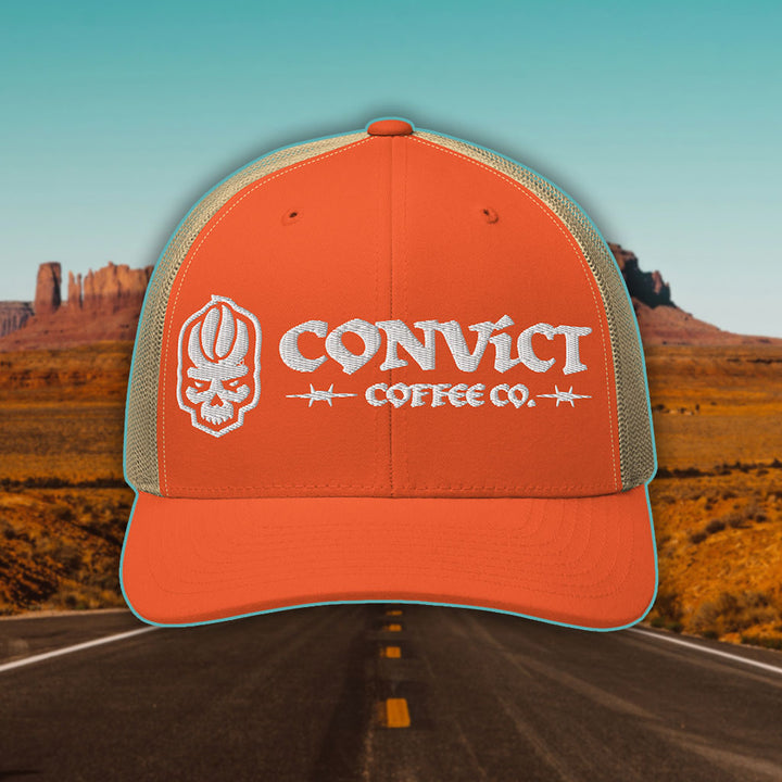 Orange and Khaki Trucker Hat with 'Convict Coffee Co.' logo white embroidery on a Desert Road background